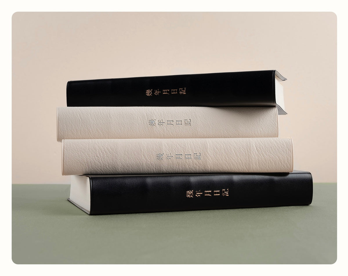 Stack of black and cream CRENA multi-year journals showing their flexible covers and thick page blocks
