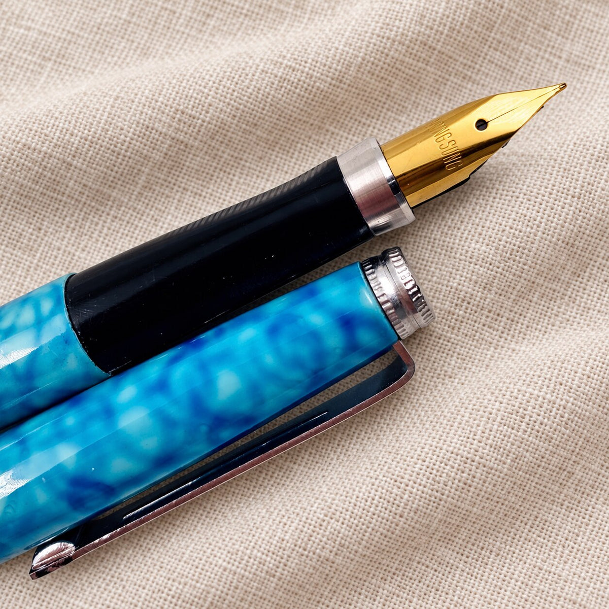 Close-up of the gold-tone steel nib and black grip on the blue marbled Wing Sung 500 fountain pen