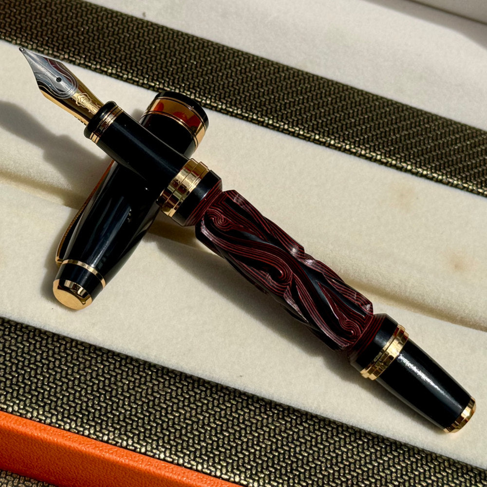 Uncapped Hero Yundiao fountain pen showing its carved red and black barrel and two-tone nib
