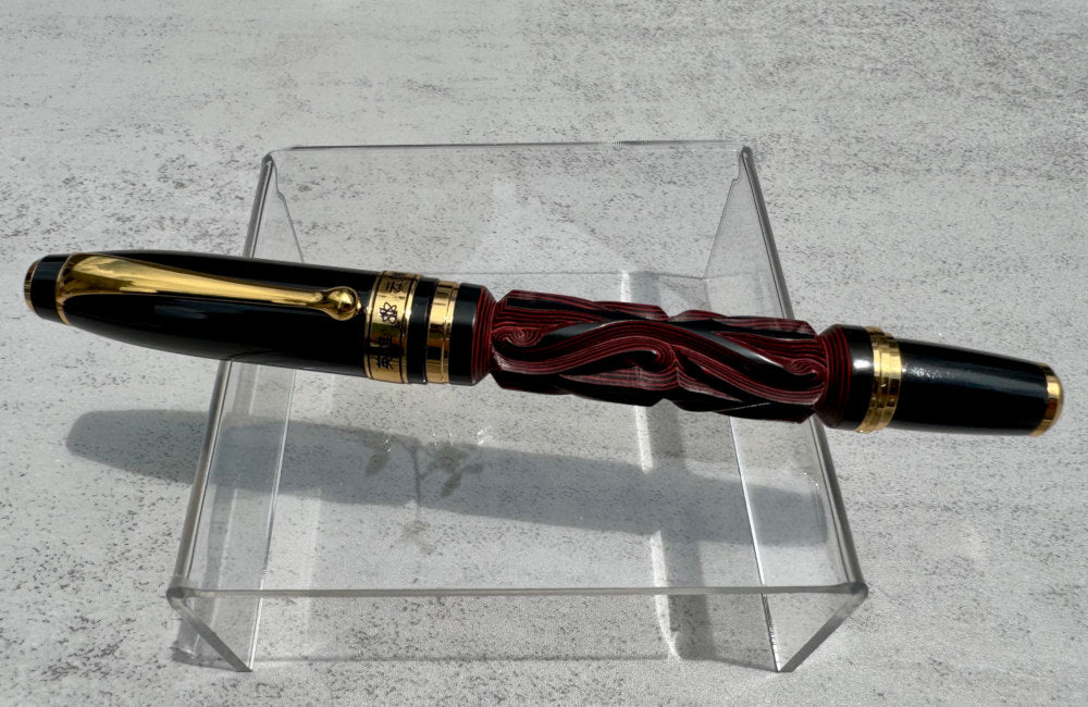 Hero Yundiao fountain pen with a carved red and black barrel, black cap, and gold-tone trim on a clear stand