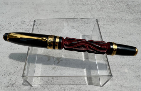 Hero Yundiao fountain pen with a carved red and black barrel, black cap, and gold-tone trim on a clear stand