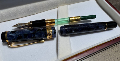 Hero 2006 fountain pen disassembled to show the green converter, nib section, blue acrylic barrel, and cap