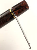 Metal piston wrench fitted around the filling knob of a brown marbled fountain pen