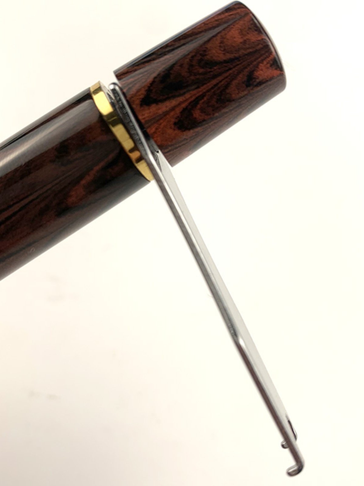 Metal piston wrench fitted around the filling knob of a brown marbled fountain pen