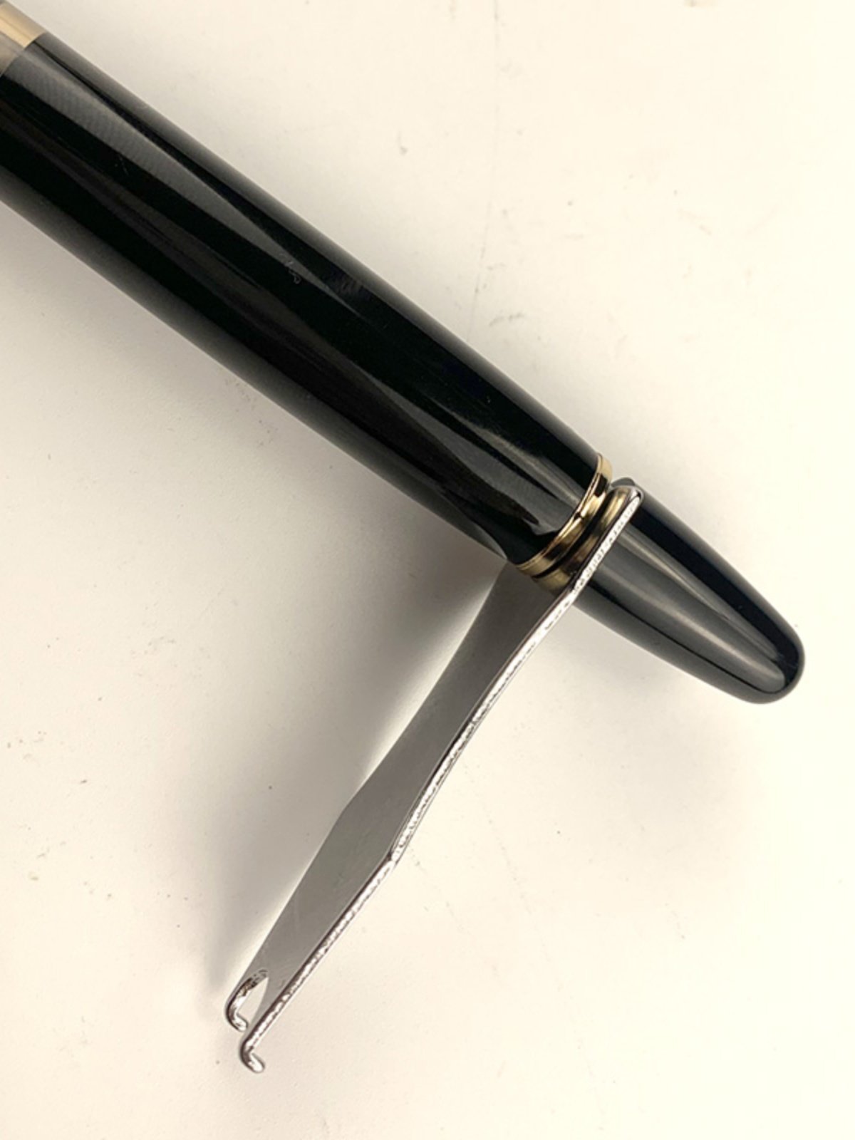 Metal piston wrench positioned at the filling knob of a black fountain pen